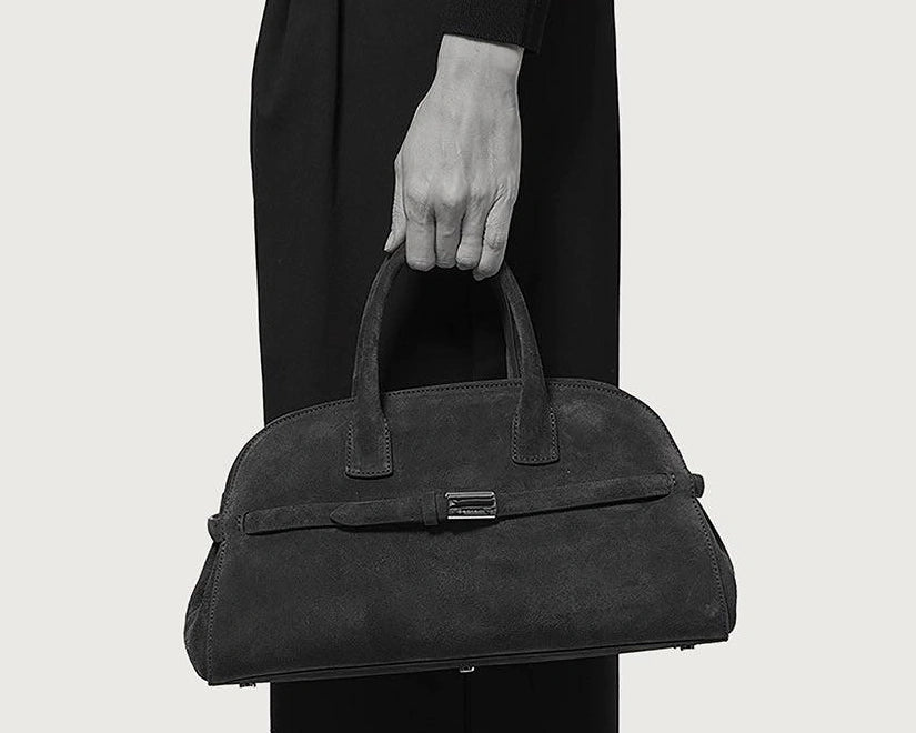 Original monochrome Orciani photograph, closely framing a hand carrying the Aura suede handbag